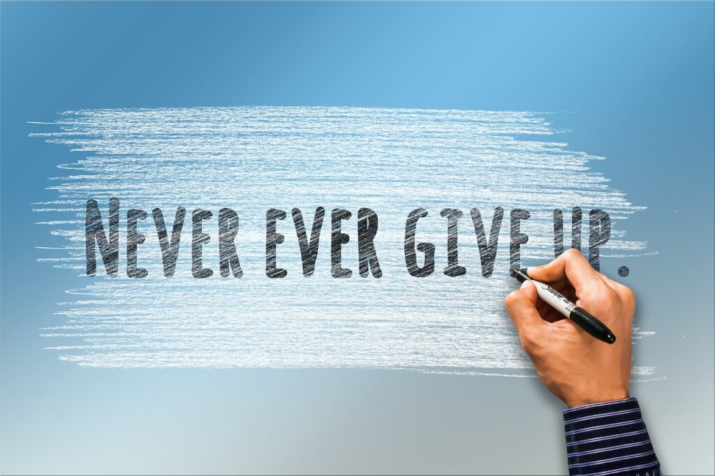 水色と白の背景に「NEVER　EVER　GIVE　UP.」と書かれている画像です。