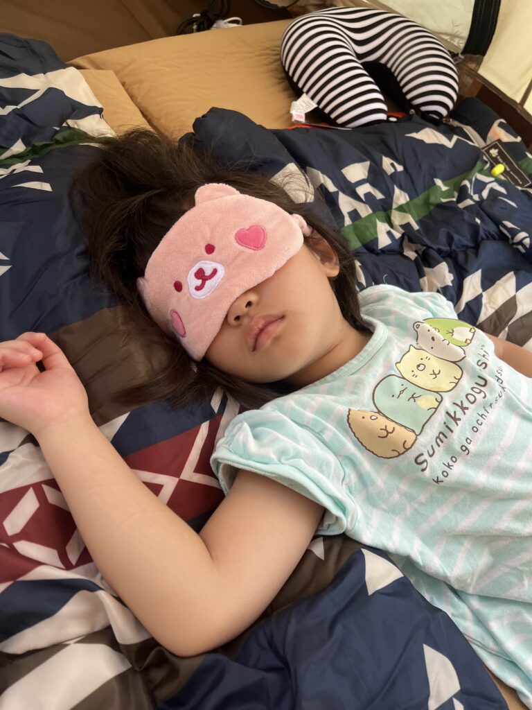 アイマスクをつけて眠っている女の子の写真です。